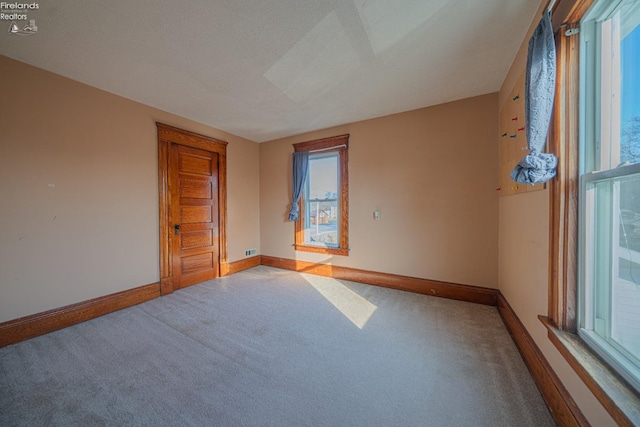 carpeted spare room with baseboards and a textured ceiling