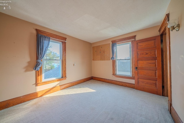 unfurnished room with baseboards, carpet floors, and a textured ceiling