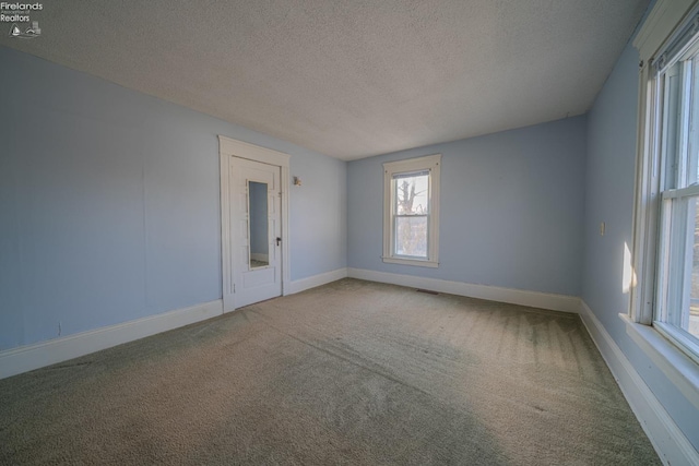 empty room with visible vents, baseboards, a textured ceiling, and carpet flooring