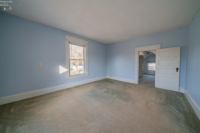 carpeted empty room with a textured ceiling and baseboards