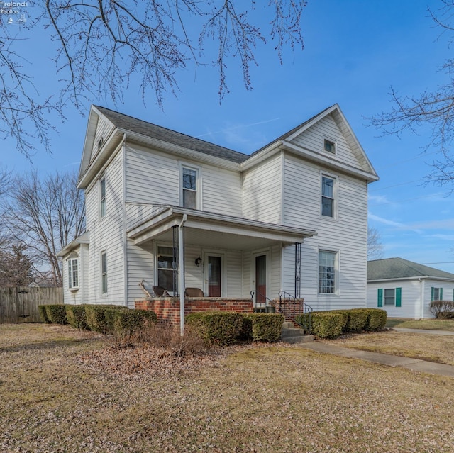 traditional-style home with covered porch, fence, and brick siding