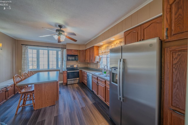 kitchen featuring a wealth of natural light, brown cabinets, appliances with stainless steel finishes, and a sink