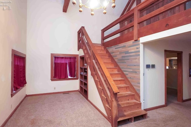 staircase with carpet floors, an inviting chandelier, a high ceiling, and baseboards