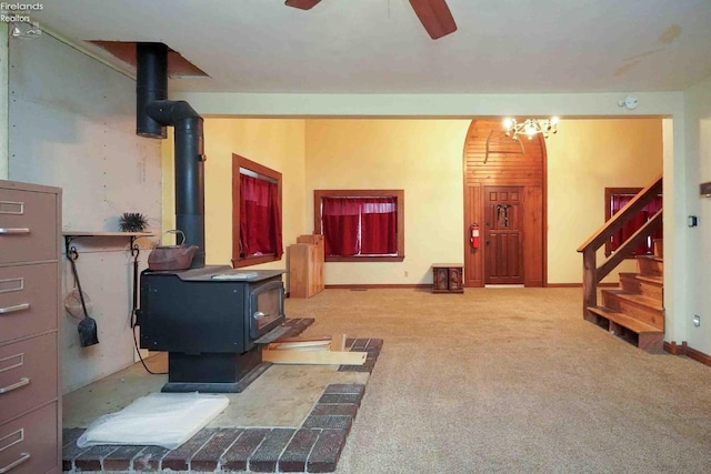 interior space with a wood stove, carpet, baseboards, and ceiling fan