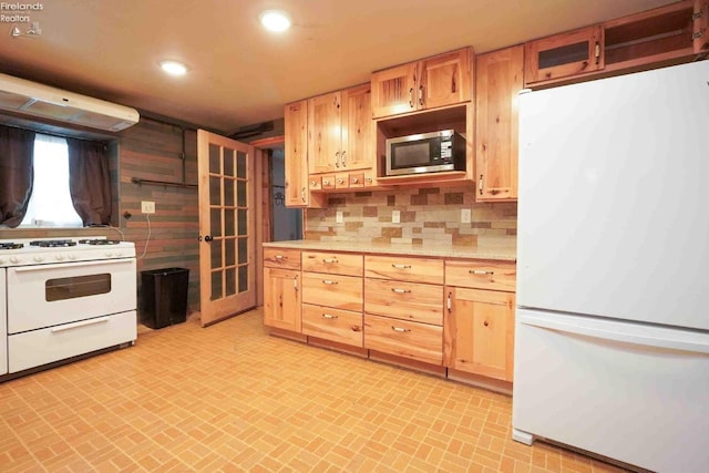 kitchen with brick floor, white appliances, light countertops, backsplash, and light brown cabinetry