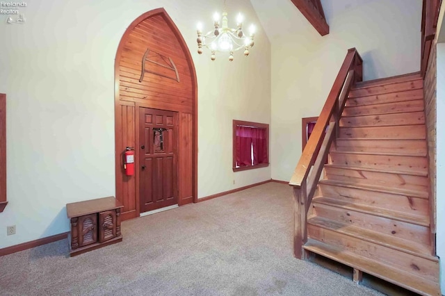 carpeted entryway with stairway, baseboards, arched walkways, and a chandelier