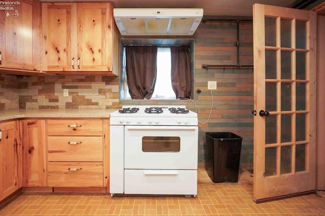 kitchen with tasteful backsplash, under cabinet range hood, white range with gas cooktop, and light countertops