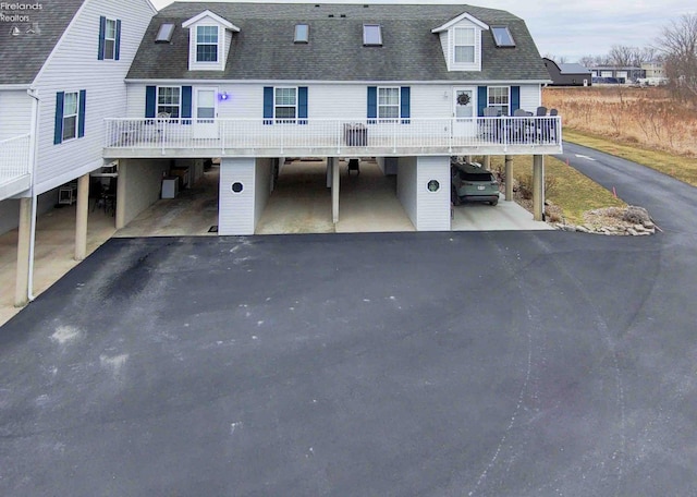 exterior space with driveway, a shingled roof, and a carport