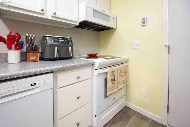 kitchen with white appliances, baseboards, white cabinets, wood finished floors, and light countertops