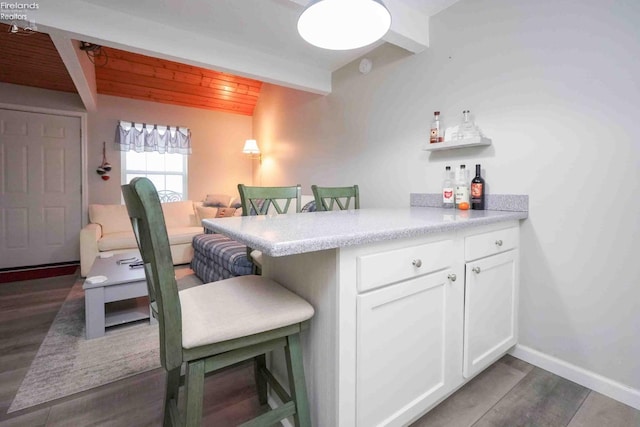 interior space with a dry bar, baseboards, wooden ceiling, dark wood-type flooring, and beam ceiling