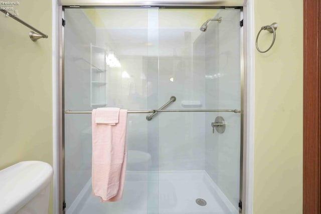 bathroom with a shower stall and toilet