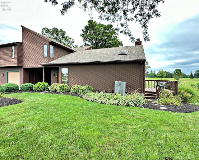 view of front of property featuring a garage, a shingled roof, a chimney, a wooden deck, and a front lawn