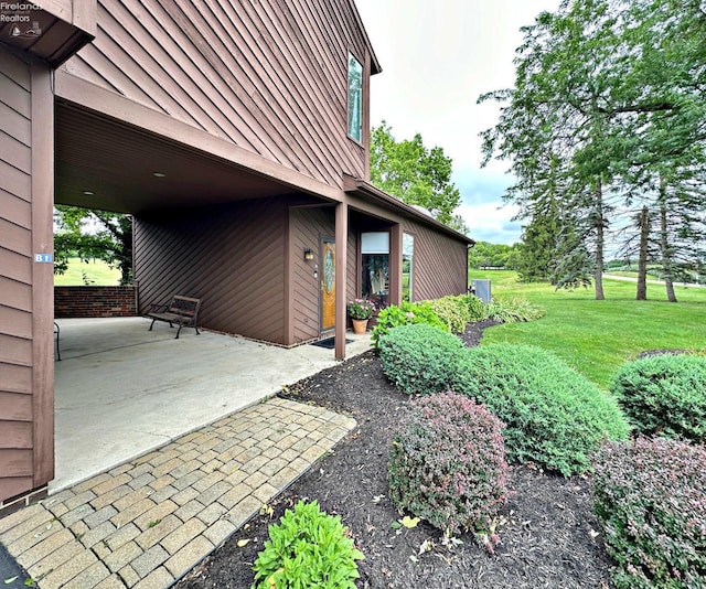 view of side of home featuring metal roof, a yard, a standing seam roof, and a patio area