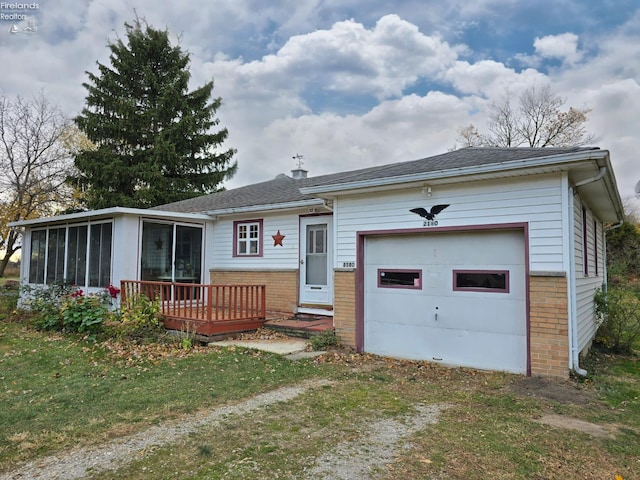 single story home with brick siding, a sunroom, a deck, a garage, and driveway