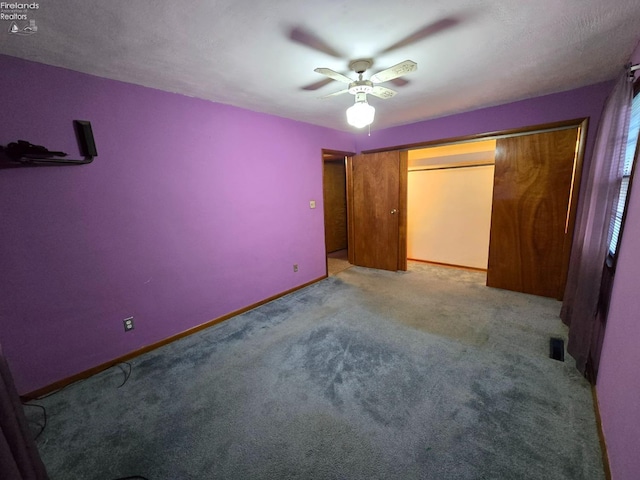 unfurnished bedroom with carpet, a closet, ceiling fan, and baseboards