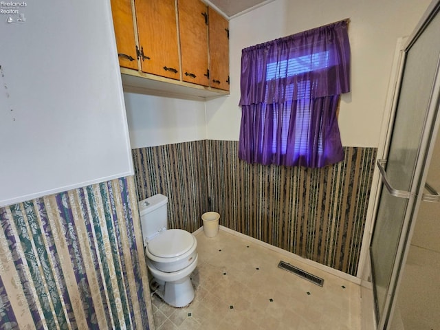 full bath featuring toilet, a stall shower, wainscoting, and visible vents