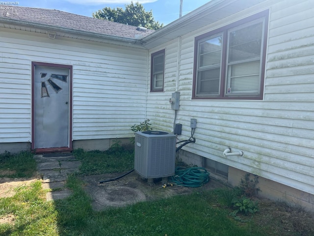 exterior space with central AC and roof with shingles