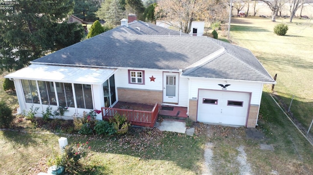 ranch-style home with a garage, brick siding, a front lawn, and a sunroom