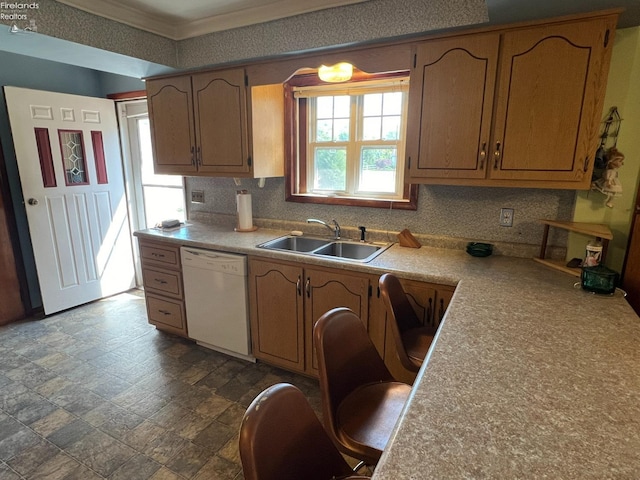 kitchen with white dishwasher, a sink, light countertops, stone finish flooring, and tasteful backsplash