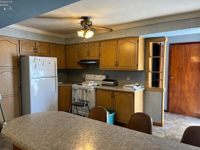 kitchen with white appliances, under cabinet range hood, brown cabinetry, and crown molding