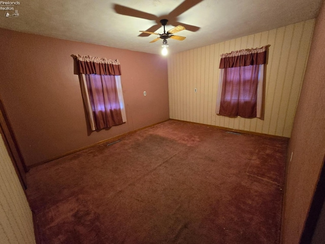 unfurnished room featuring baseboards, carpet flooring, visible vents, and a ceiling fan