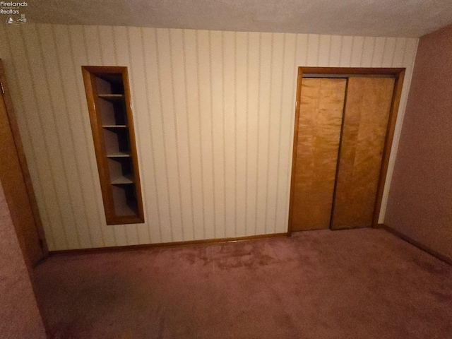 unfurnished bedroom featuring carpet, a closet, and wallpapered walls