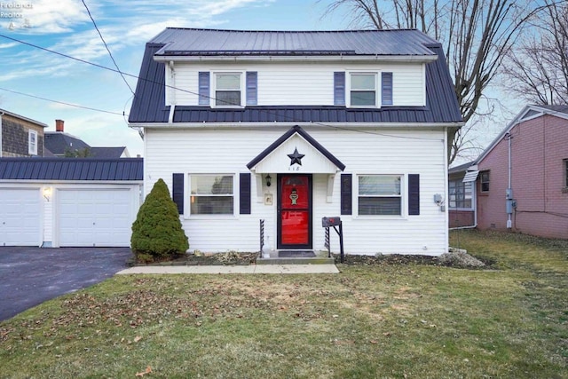 colonial inspired home with aphalt driveway, an attached garage, metal roof, and a front lawn