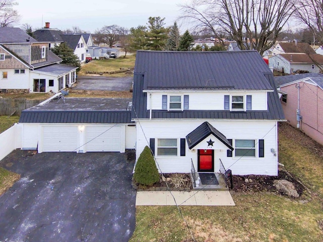 view of front of property with driveway, a residential view, metal roof, an attached garage, and fence