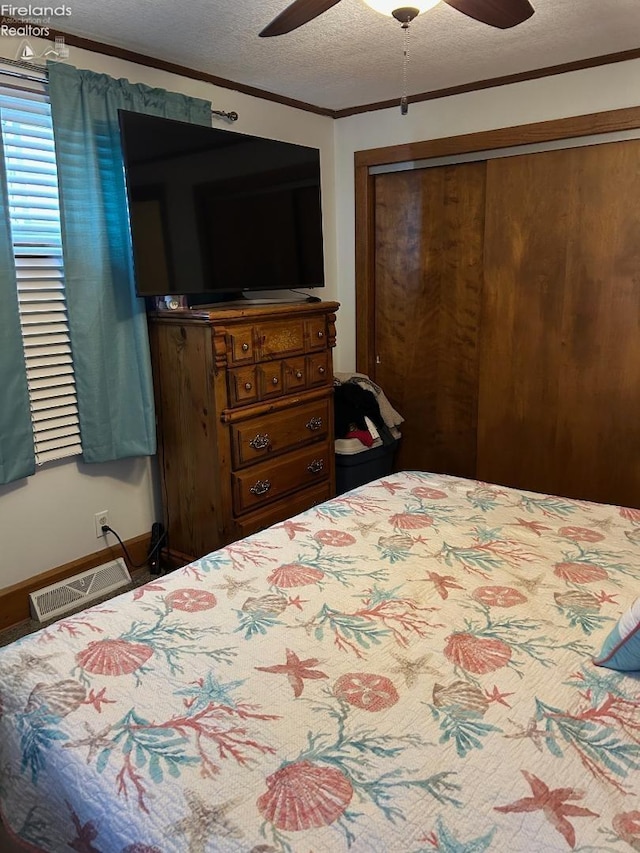 bedroom featuring crown molding, a closet, visible vents, a ceiling fan, and a textured ceiling