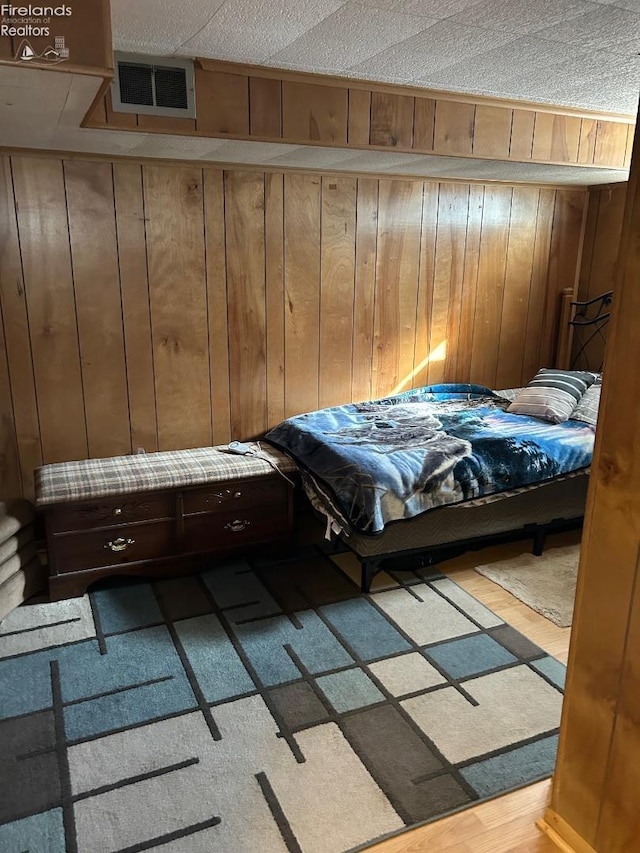 bedroom featuring visible vents and wooden walls