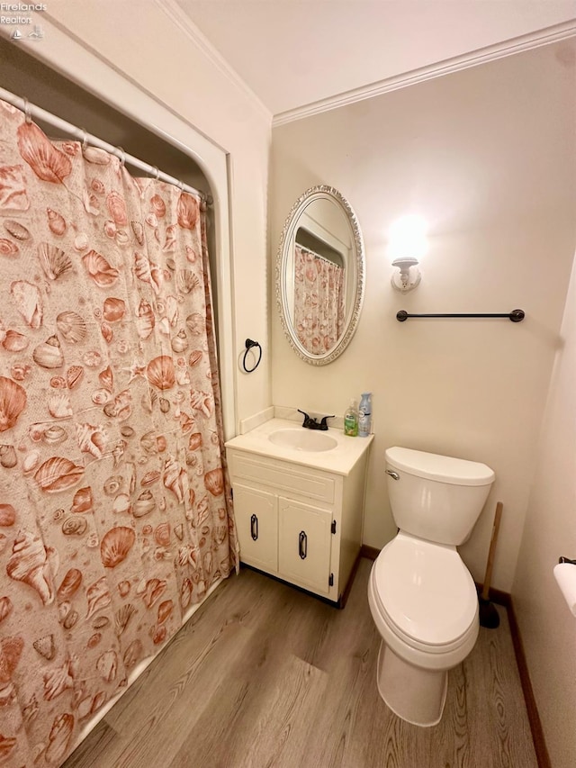 bathroom featuring vanity, ornamental molding, wood finished floors, toilet, and baseboards
