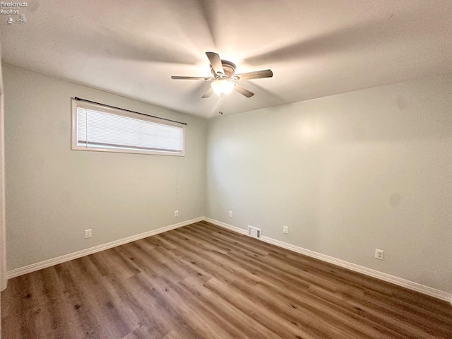 unfurnished room with baseboards, ceiling fan, visible vents, and wood finished floors