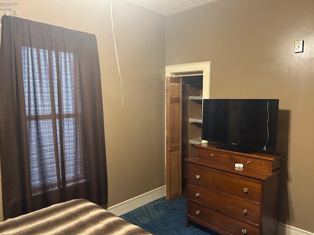 bedroom with dark colored carpet and baseboards