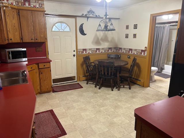 dining space with light floors, crown molding, and wainscoting