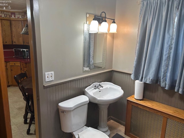 bathroom featuring toilet, tile patterned floors, radiator heating unit, and wainscoting