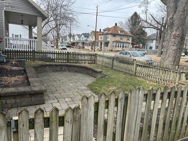 view of yard featuring a fenced front yard, a residential view, a porch, and a patio