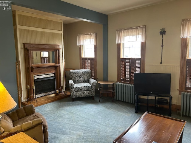 living area featuring a wainscoted wall, carpet floors, radiator heating unit, and a fireplace