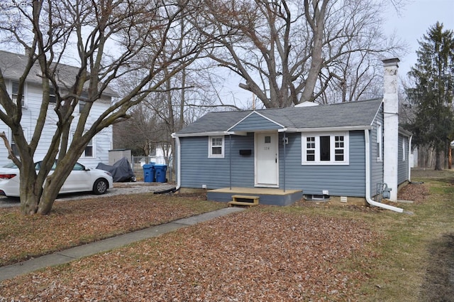 view of front of home with a shingled roof and a chimney