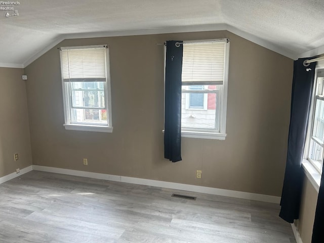 bonus room with visible vents, vaulted ceiling, a textured ceiling, and baseboards