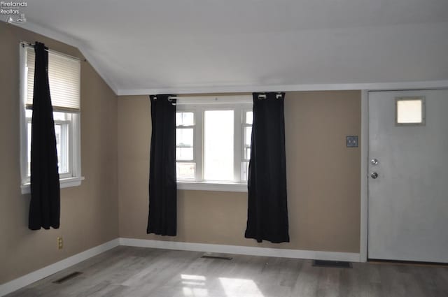 entrance foyer with lofted ceiling, baseboards, visible vents, and wood finished floors