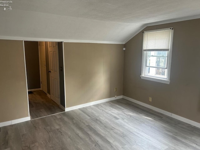 additional living space with lofted ceiling, baseboards, and wood finished floors