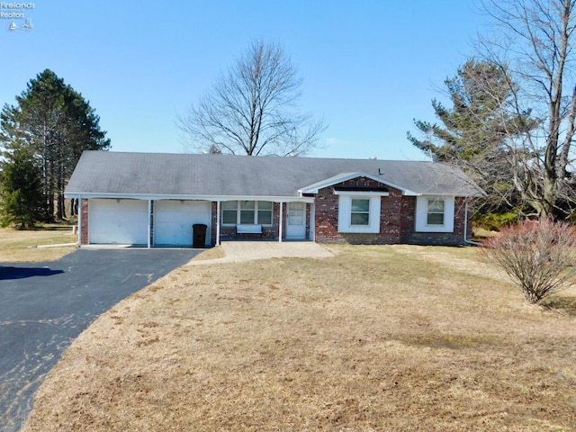 ranch-style house with aphalt driveway, a front yard, brick siding, and an attached garage