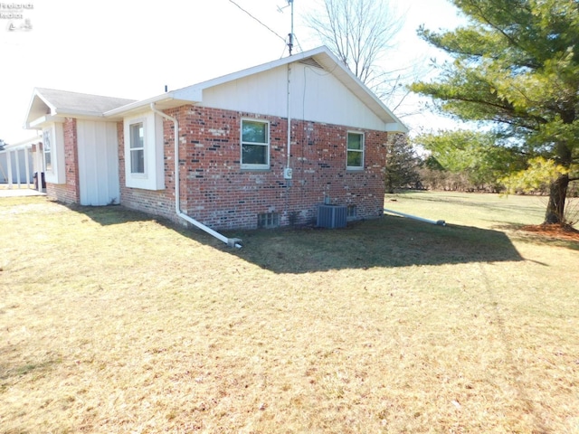 view of side of property featuring central air condition unit, a lawn, and brick siding