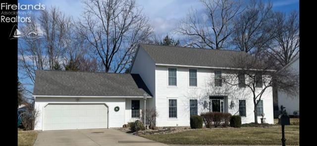 colonial home featuring a garage, driveway, and a front yard