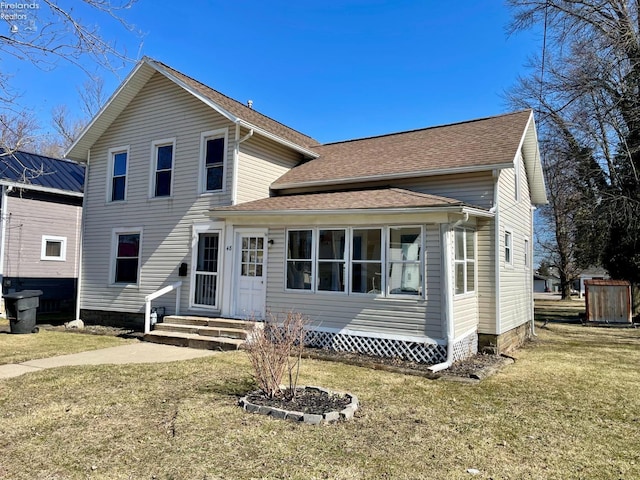 traditional home with entry steps, a shingled roof, and a front yard