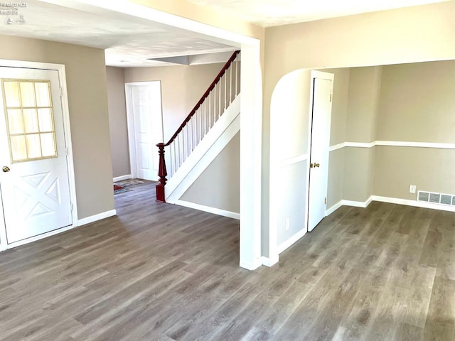 foyer entrance featuring visible vents, baseboards, wood finished floors, and stairway