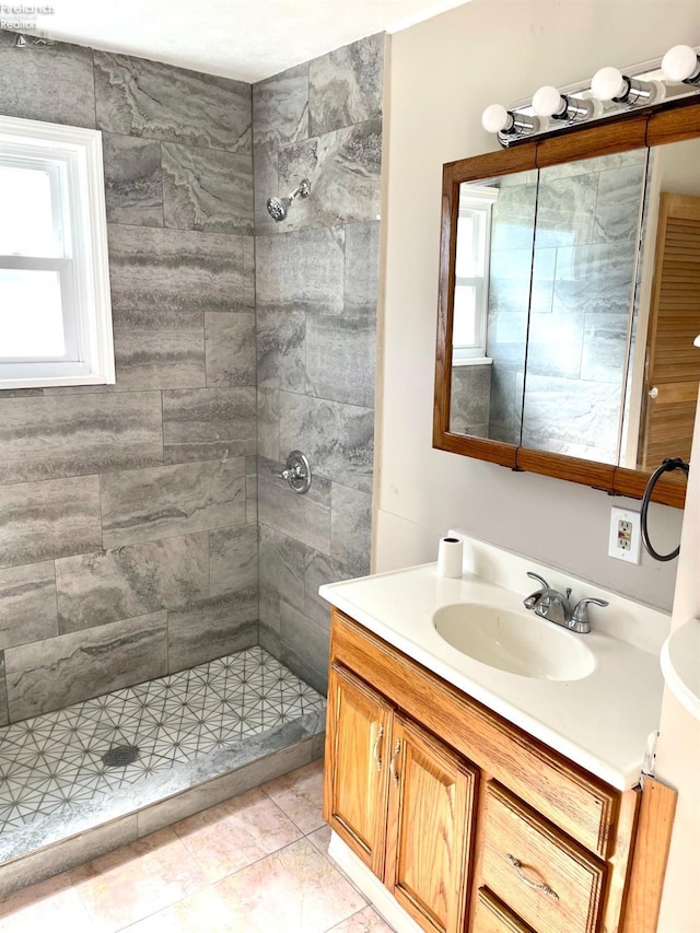 full bath featuring a tile shower, tile patterned flooring, and vanity