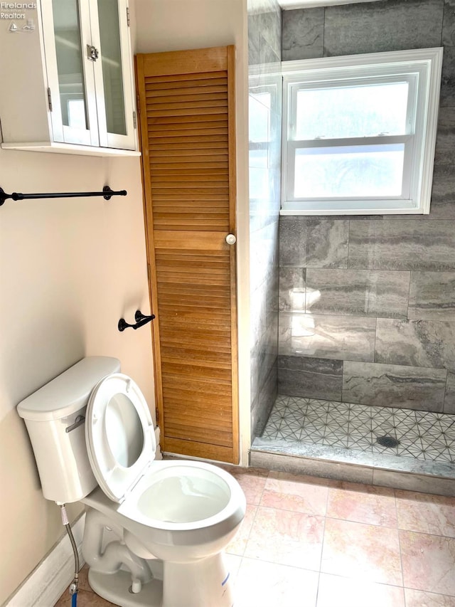 bathroom with toilet, a shower stall, and tile patterned flooring