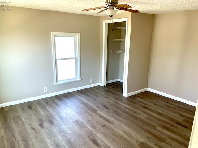 unfurnished bedroom with a textured ceiling, dark wood finished floors, a closet, baseboards, and ceiling fan