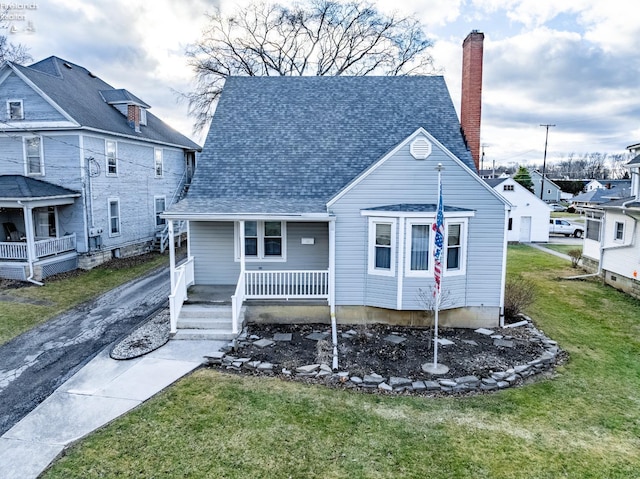 view of front facade with a porch, a chimney, a front lawn, and roof with shingles